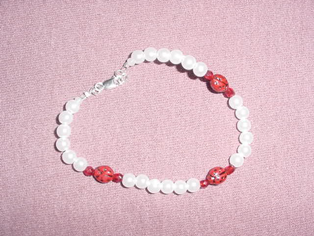 Faux white beads, czech ruby red beads and czech ladybug beads with sterling silver lobster claw clasp and findings.